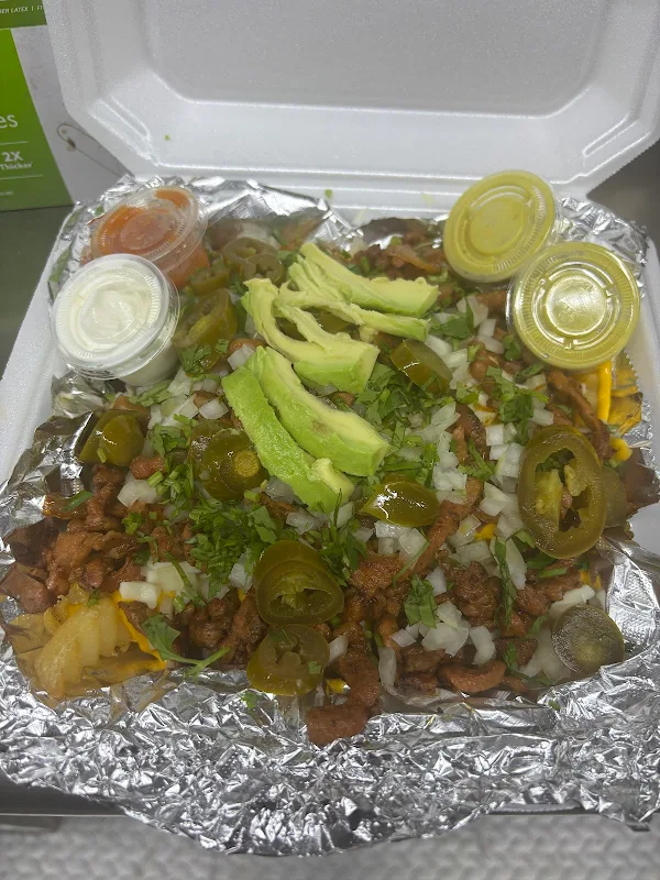 Loaded asada fries with avocado, cheese, jalape&ntilde;os, crema, and salsa